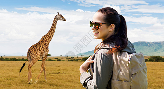 旅行,旅游人的快乐的轻女人背包非洲大草原长颈鹿的背景带着背包非洲旅行的快乐女人图片