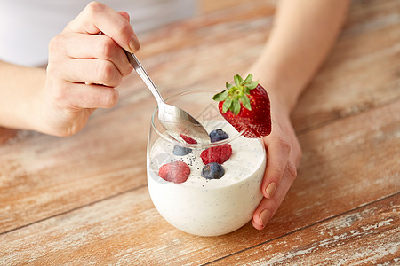 健康的饮食,食物人的靠近女人的手与酸奶浆果璃桌子上女人手里着酸奶浆果桌子上图片