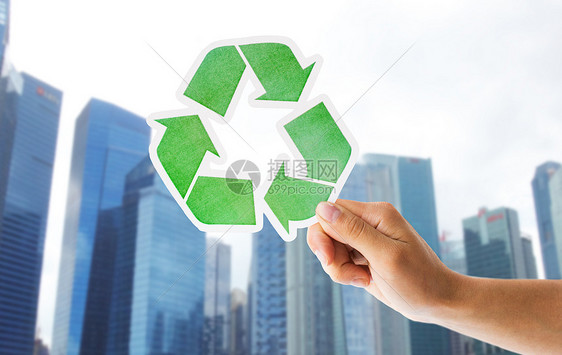 垃圾处理环境生态城市摩天大楼背景下,手握绿色回收标志城市用绿色回收标志手图片