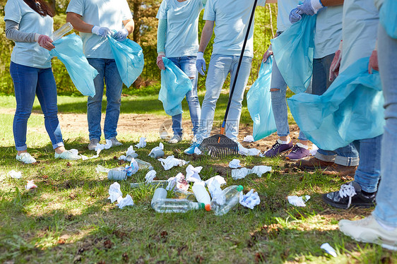 志愿服务慈善人与生态理念公园内群带垃圾袋耙清理区域的志愿者志愿者用垃圾袋清洁公园区域图片