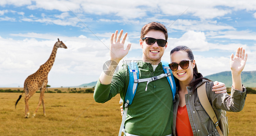 旅行,徒步旅行,背包旅行,旅游人的幸福的夫妇与背包挥手非洲大草原长颈鹿的背景微笑的夫妇背包非洲旅行图片