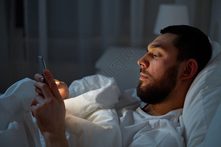 技术,通信人的男人智能手机上发短信家里晚上晚上床上智能手机的男人图片