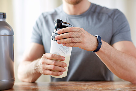 运动,健康的生活方式人们的接近男人穿着健身追踪器与罐子瓶子准备蛋白质奶昔用蛋白瓶罐子把人关来图片