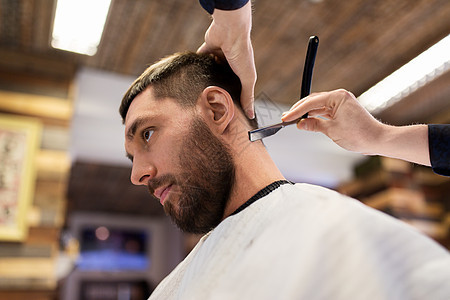美容人的男人理发师与直剃刀剃须颈部头发理发店男人理发师用直剃刀剃头发图片