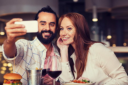 休闲,技术,约会,人假日的快乐的夫妇餐厅吃晚饭用智能手机自拍夫妇餐厅用智能手机自拍图片