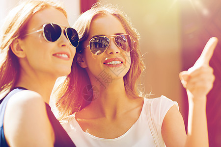 夏天,时尚,配饰人们的快乐的女人戴着太阳镜指着城市戴太阳镜的快乐女人户外指指点点图片