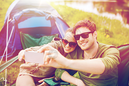 旅行,徒步旅行,技术,旅游人的微笑的旅行者露营时用智能手机自拍几个旅行者用智能手机自拍图片