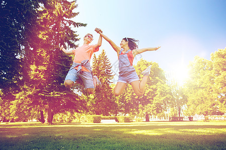 假期,爱人的快乐的微笑青少夫妇夏季公园跳跃快乐的十几岁的夫妇夏天的公园跳图片