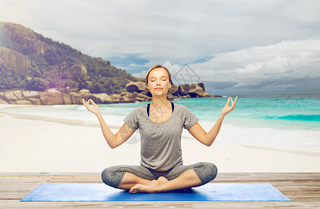 健身,人们健康的生活方式妇女异国情调的热带海滩背景的垫子上莲花姿势的瑜伽冥想海滩上莲花姿势瑜伽冥想的女人图片