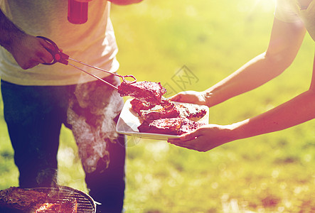 食物,人,吃烹饪的男人着钳子夏天的聚会上把烤肉放盘子里男人夏天的聚会烧烤上饭图片