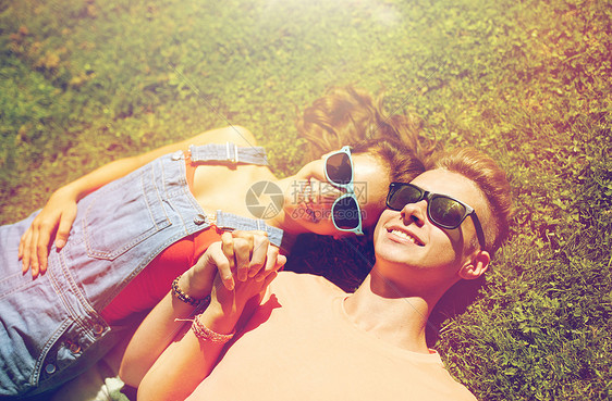 爱人的快乐的轻夫妇戴着太阳镜躺草地上夏天快乐的十几岁的夫妇夏天躺草地上图片