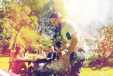 休闲,食物,人假日的男子烹饪肉烧烤为他的朋友夏季户外聚会夏天的聚会上,男人烧烤架上煮肉图片
