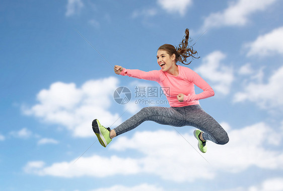 运动,健身,运动人的快乐的轻女人空中跳跃,蓝天云层背景上的战斗姿势快乐运动的轻女人跳战斗姿势图片