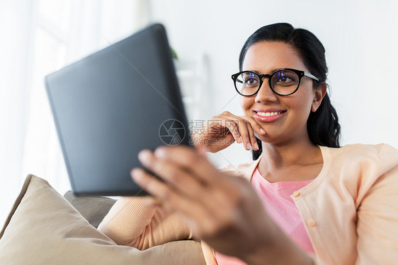 人,技术休闲快乐的轻印度妇女坐沙发上与平板电脑电脑家里快乐的印度女人家里平板电脑图片