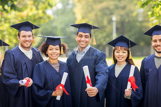 教育,毕业人的群快乐的国际学生迫击炮板学士学位礼服与文凭文凭的迫击炮板上快乐的学生图片