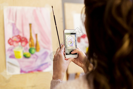 技术,创造力人的女艺术家学生与智能手机刷子摄影静物绘画图片艺术学校工作室艺术学校的智能手机上画画的女人图片