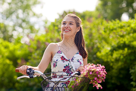 人们,休闲生活方式快乐的轻时髦女人穿着夏装,骑着固定自行车,公园的篮子里放着野花快乐的女人夏天的公园骑固定自行车图片