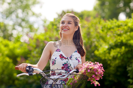 人们,休闲生活方式快乐的轻时髦女人穿着夏装,骑着固定自行车,公园的篮子里放着野花快乐的女人夏天的公园骑固定自行车图片