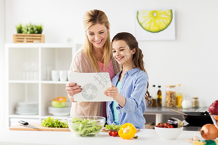 健康饮食,家庭人的快乐的母亲女儿烹饪蔬菜晚餐用线食谱平板电脑电脑家庭厨房家庭烹饪晚餐用平板电脑厨房图片