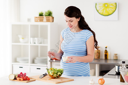 健康饮食,怀孕,食物人的孕妇烹饪蔬菜沙拉与羊奶酪家里厨房孕妇家煮蔬菜沙拉图片