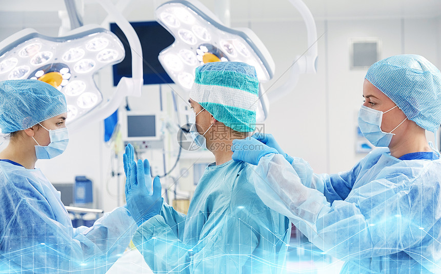 外科,医学人的护士协助外科医生,并帮助手套防护穿手术室医院医院手术室的外科医生图片