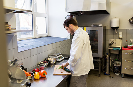 烹饪食物,职业人的快乐的男厨师用刀切黄瓜餐厅厨房的砧板上饭快乐的男厨师餐厅厨房烹饪食物背景图片
