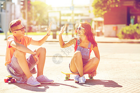 暑假,极限运动,手势人的快乐的十几岁的夫妇与短的现代巡洋舰滑板城市街道上高五轻夫妇城市街道上滑板图片