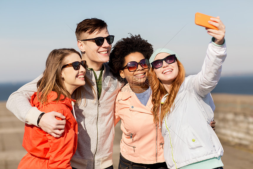 人,友谊技术群微笑的十几岁的朋友户外用智能手机自拍快乐的朋友户外用智能手机自拍图片
