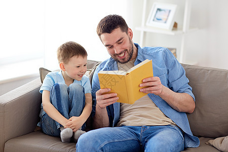 家庭,童,父爱,休闲人的幸福微笑的父亲小儿子家里沙发上读书的肖像快乐的父子家看书沙发图片