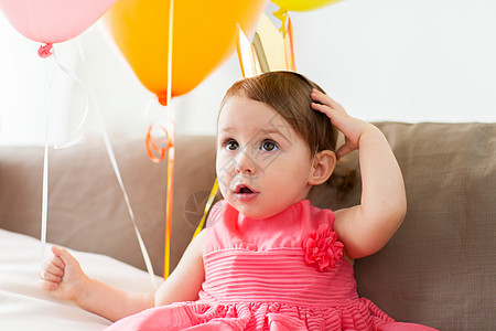童,人庆祝快乐的女婴戴着皇冠家里的生日聚会家里的生日聚会上,皇冠上的快乐女婴图片