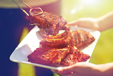 食物,人,吃烹饪的男人着钳子夏天的聚会上把烤肉放盘子里男人夏天的聚会烧烤上饭图片