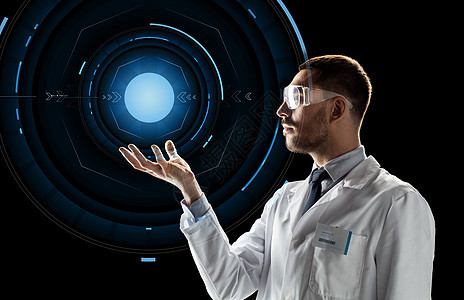 男科学家穿实验室外套戴护目镜在黑色背景与虚拟投影上图片
