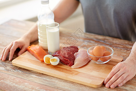 运动营养,健康饮食人的密切的男手与富含蛋白质的食物木制切割板把食物中富含蛋白质的人关来背景图片