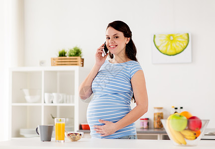 怀孕,人健康的饮食快乐的孕妇打电话给智能手机,家里的厨房吃早餐快乐的孕妇家里打电话给智能手机图片