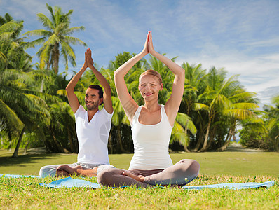 健身,运动,瑜伽人们的快乐的夫妇冥想莲花姿态户外异国情调的自然背景与棕榈树夫妇户外莲花姿势的瑜伽图片