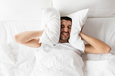 休息的男人躺床上被噪音困扰图片