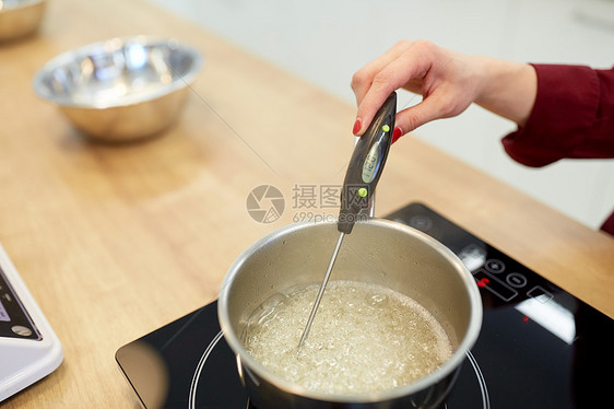 烹饪,食品厨房用具的厨师与温度计测量温度糖糖浆沸腾锅炉子上厨师厨房测量糖浆中的温度图片