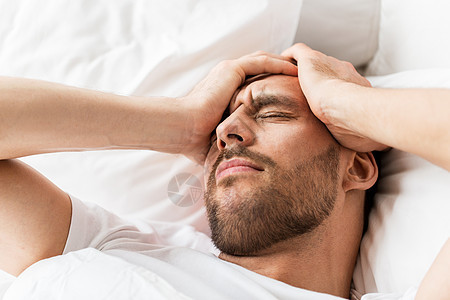躺在床上患头痛的男人图片