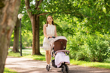 公园散步推宝宝家庭,母亲人的快乐的母亲与孩子睡婴儿车夏季公园散步快乐的母亲孩子婴儿车夏季公园背景