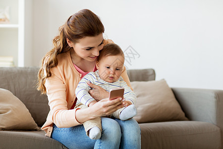 家庭,技术母亲的快乐的微笑轻母亲与小婴儿智能手机家里快乐的母亲带着孩子智能手机家图片
