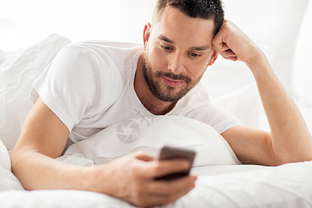 个男人床上玩手机休息图片
