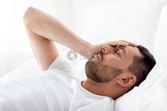人,睡觉时间休息的男人躺床上,患头痛宿醉家卧床的人头痛图片