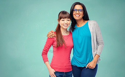 学校,教育人的两个快乐微笑的国际女学生绿色粉笔板背景国际学生学校粉笔板图片