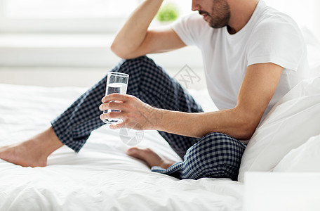 人,睡觉时间休息的男人床上喝杯水家家里杯水躺床上的男人图片