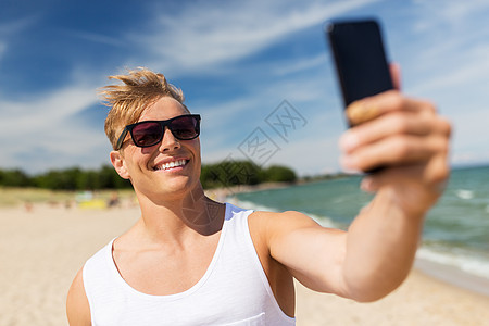 暑假人们的快乐的微笑轻人与智能手机海滩上自拍智能手机的男人夏天的海滩上自拍图片