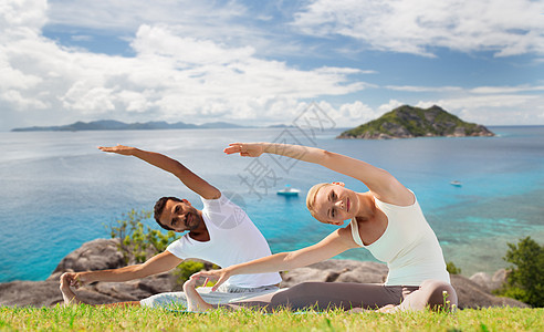 健身,运动,人娱乐活动微笑的夫妇瑜伽练坐户外的垫子上的海洋背景微笑的夫妇户外瑜伽练背景图片