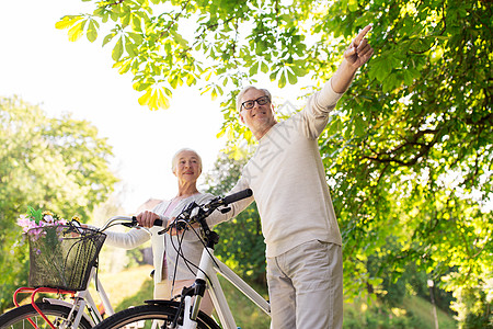 老人,人生活方式的快乐的老夫妇步行与固定自行车夏季城市公园快乐的老夫妇夏季公园骑自行车图片