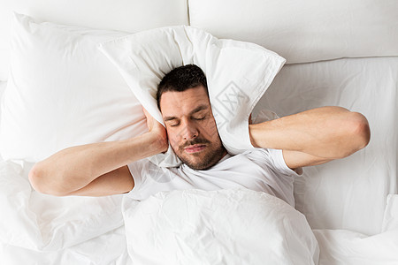 人们,睡觉时间休息的男人躺床上,枕头家里被噪音所困扰男人躺床上,枕头上噪音背景图片