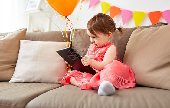 童,假期人的快乐的女婴与平板电脑气球生日聚会家里家里平板电脑的女婴生日聚会上图片