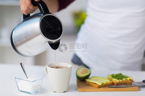 食物,健康饮食,人饮食男人用水壶泡茶家里厨房吃鳄梨三明治早餐带水壶的男人家早餐茶图片